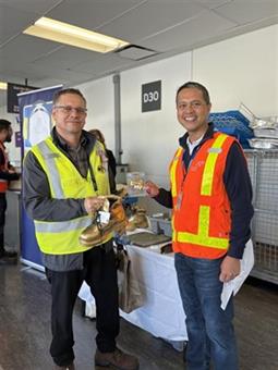a couple of men wearing safety vests and holding a tray of food