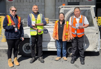 a group of men wearing safety vests and standing in front of a truck