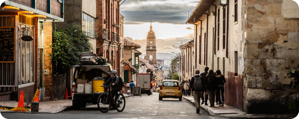 a person riding a bicycle down a street with a cart and people walking