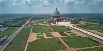 a large building with a dome on top of a grassy hill