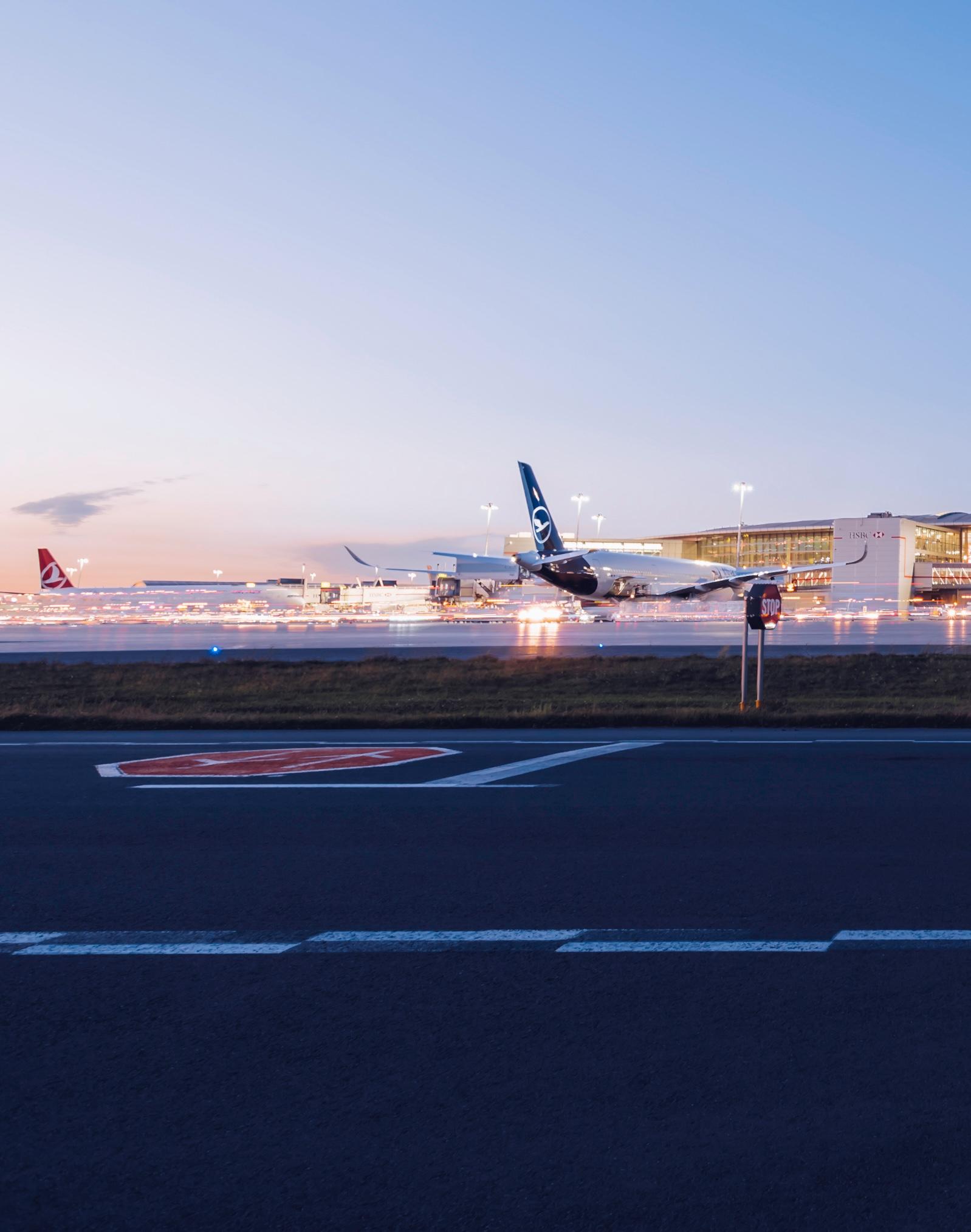 A view of a Toronto Pearson terminal at dusk. There are planes from several airlines parked at gates.