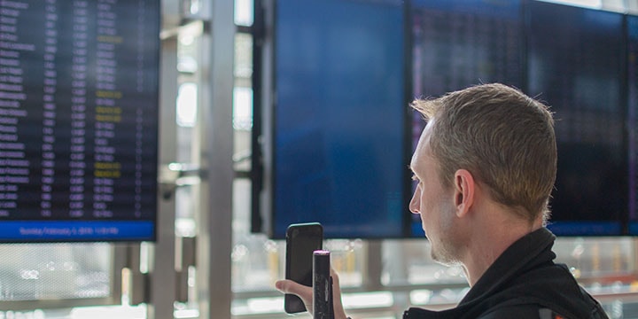 man using the Aira app at Pearson airport in front of FIDS