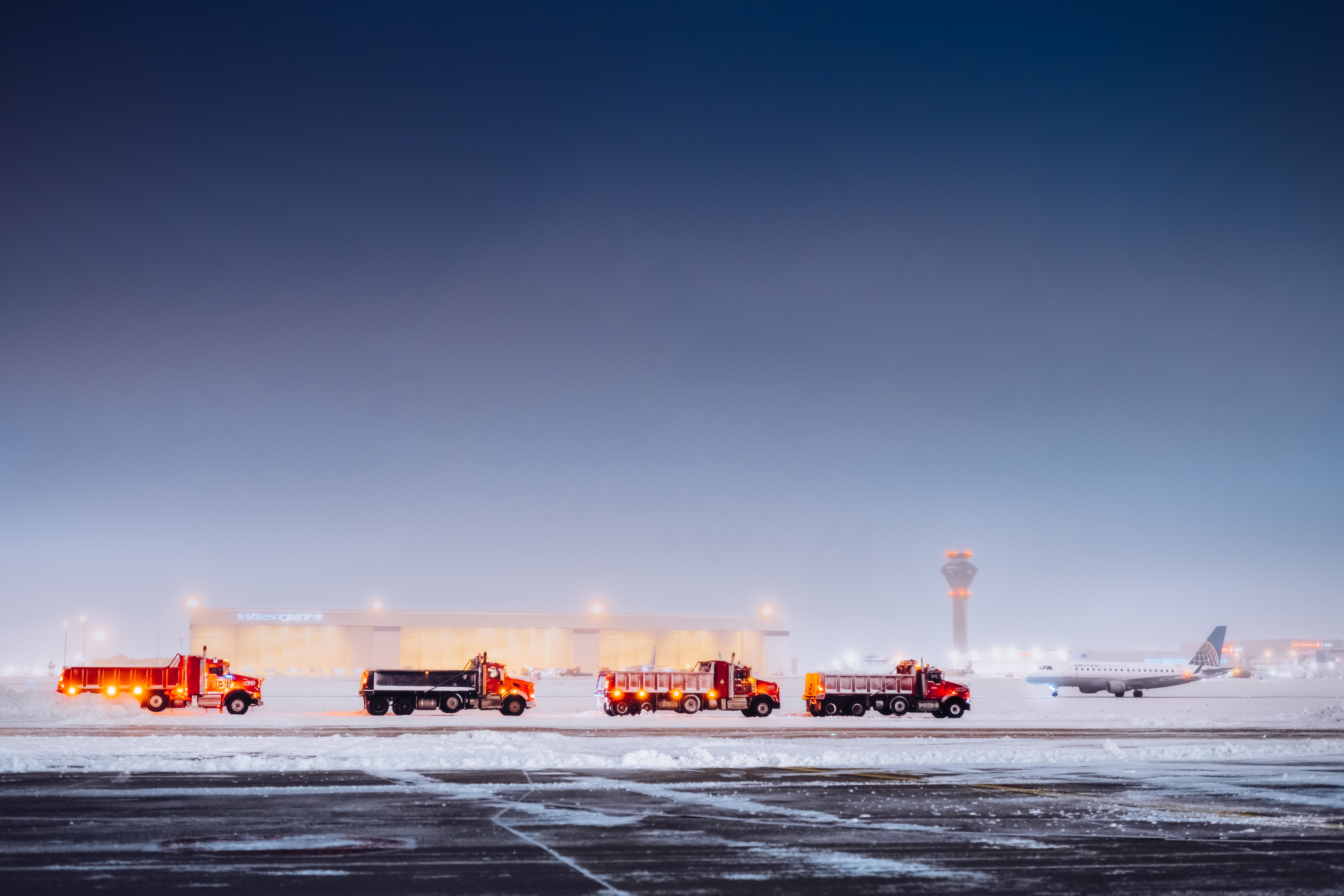 a group of fire trucks in front of an airplane on a runway