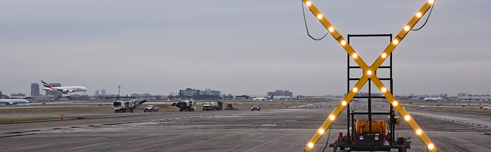 A lit-up warning sign on a runway indicating ongoing electrical maintenance work.