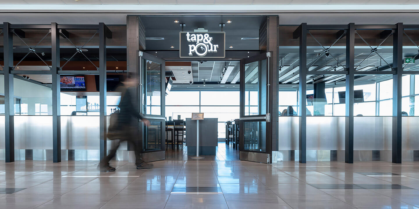 Tap and Pour sign above glass walls and entrance to the restaurant