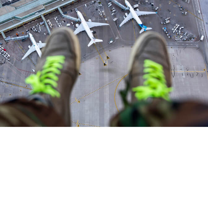 The feet of someone sitting high above airplanes parked at Toronto Pearson Airport