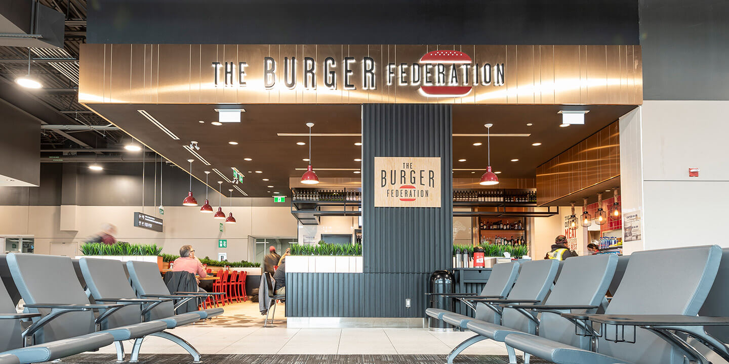Vue du restaurant ouvert de Burger Federation avec l’enseigne en cuivre et des tables
